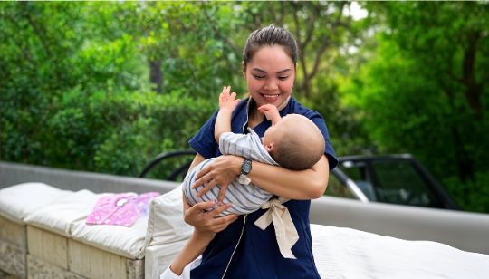 Happy caregiver holding a baby outdoors