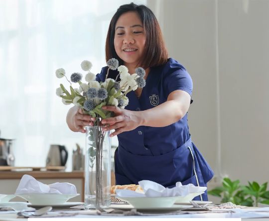 Housekeeper putting flowers in cloudy vase